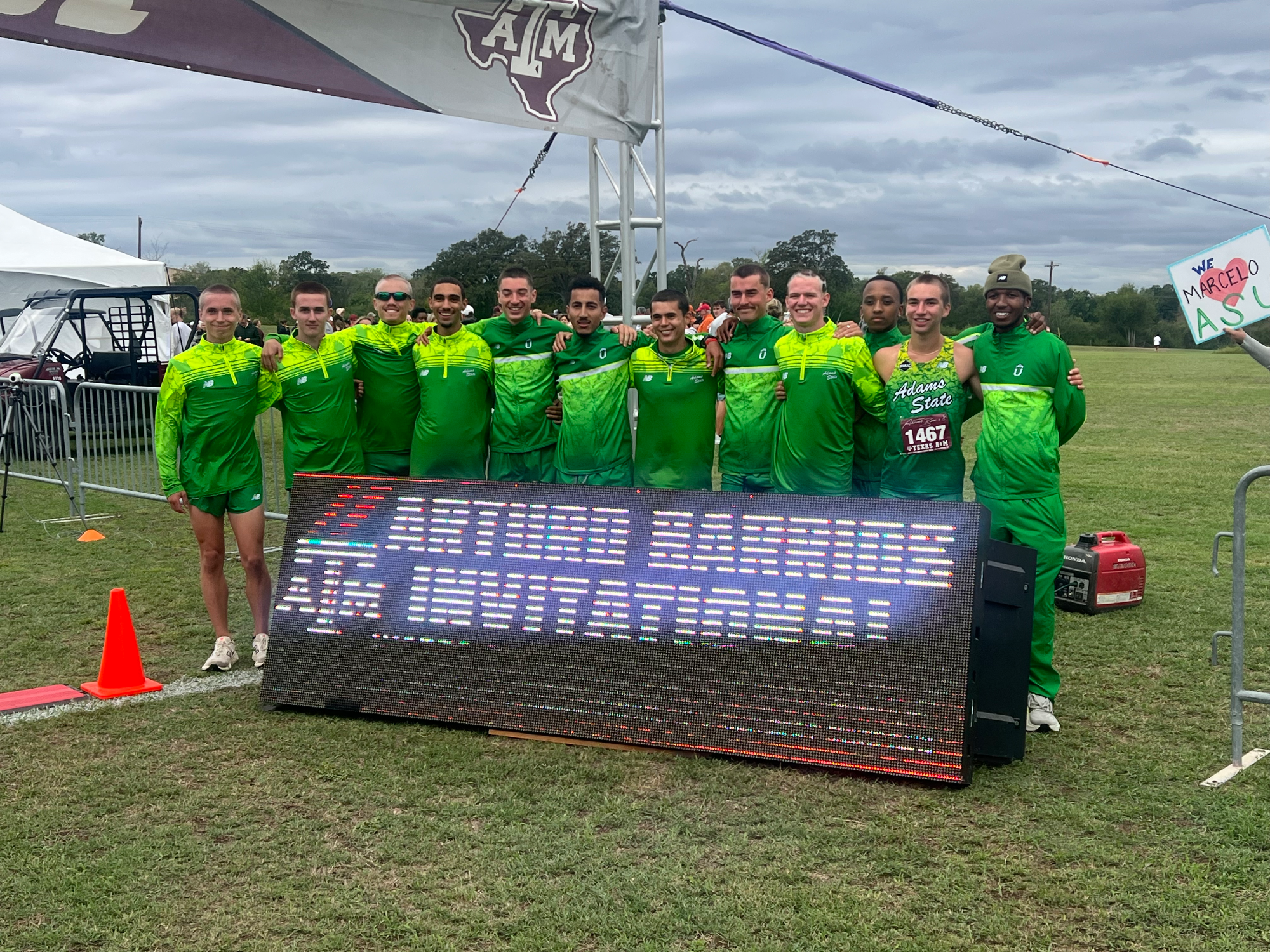 Men XC team pose behind the Artro invite poster after they claim 1st Place 