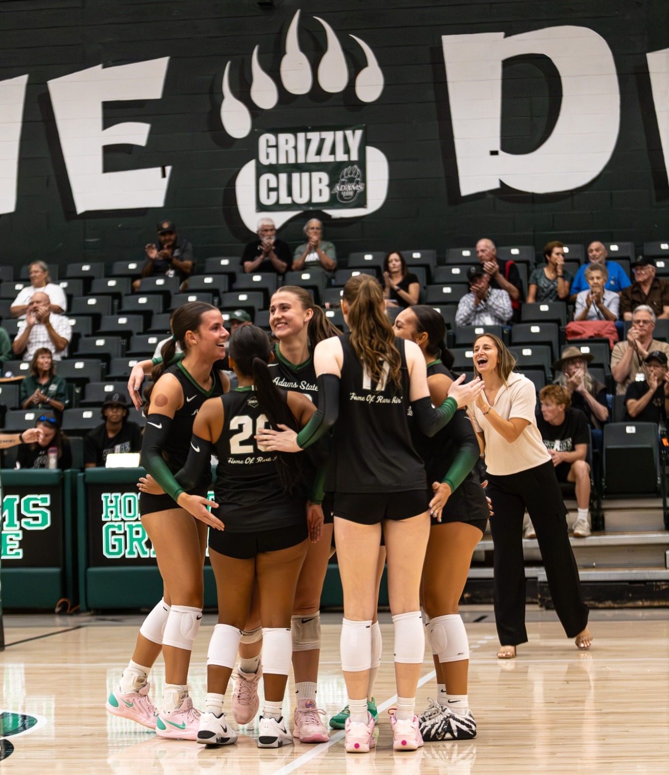 Picture of the five women on the court at home celebrating a point win.