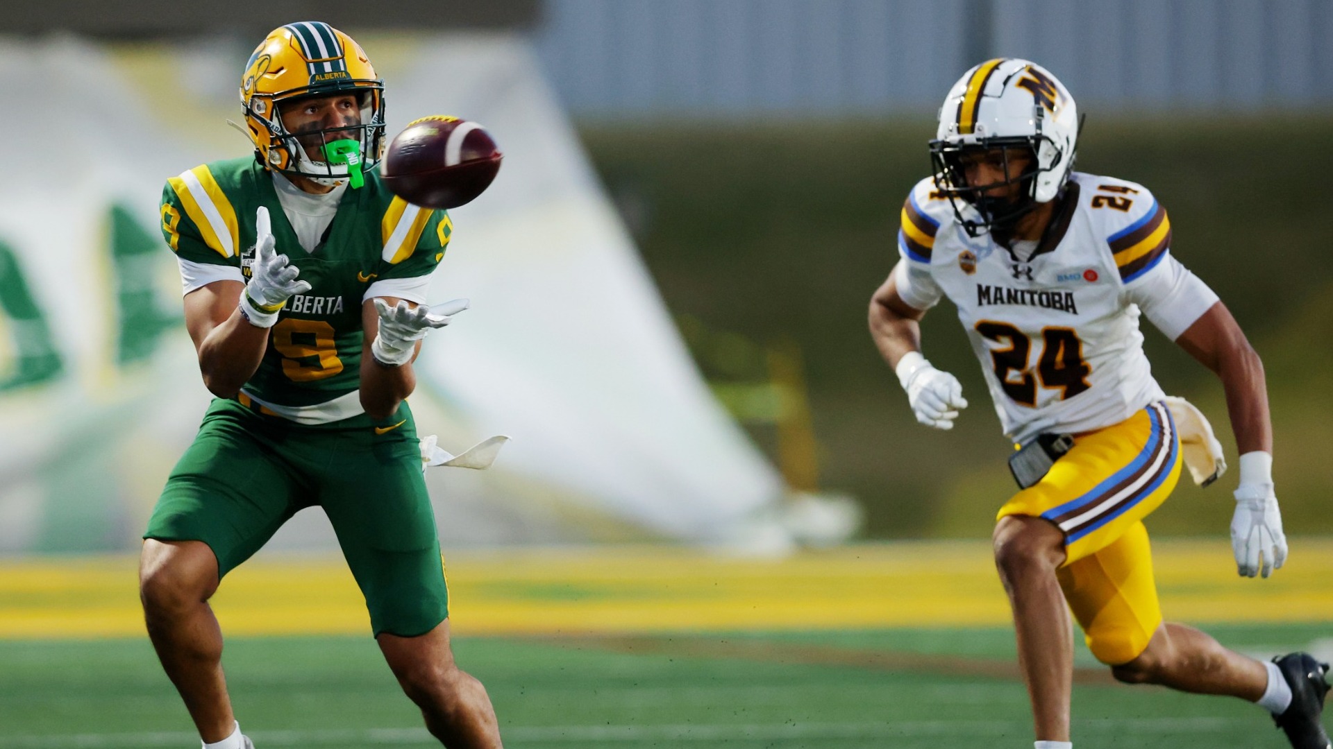 Isaiah Edwards has his hands out to make a catch while a defender runs towards him
