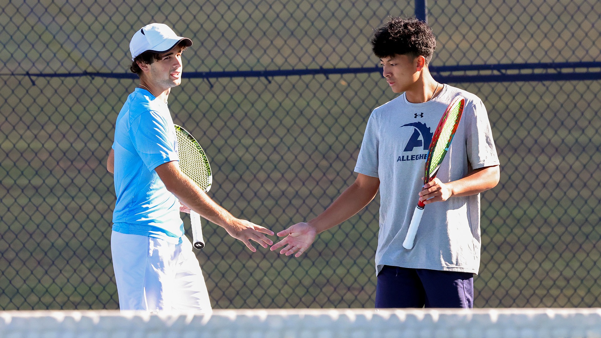Zidaan Hassan (L), Adam Memije (R) high-five during men's tennis doubles match, 2025. Photo by Ed Mailliard.