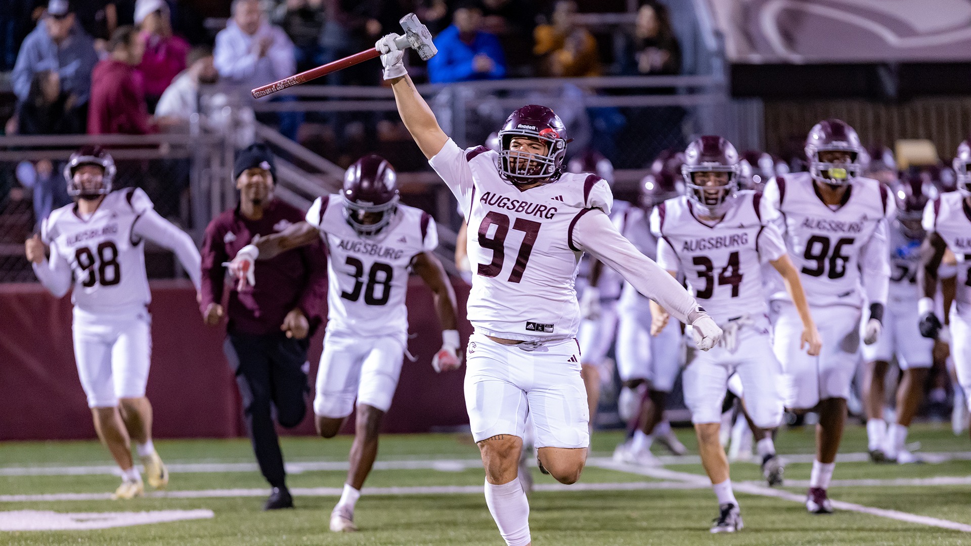 Tayvion Gardner runs with The Hammer trophy after Augsburg's final win of the 2025 football season.