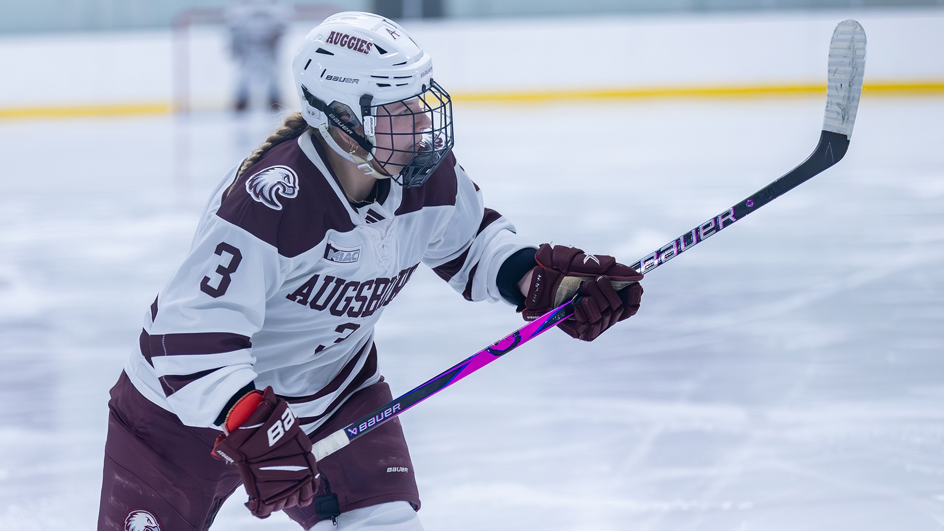 Ella Olson raises her stick during a 2025-26 Augsburg women's hockey game.