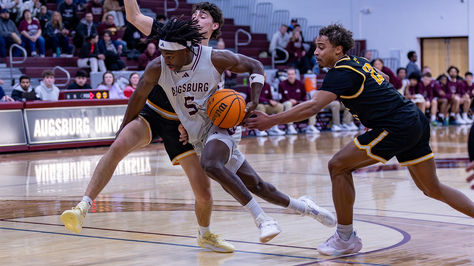 Elias Batala drives against an opponent during a 2025-26 Augsburg men's basketball game.