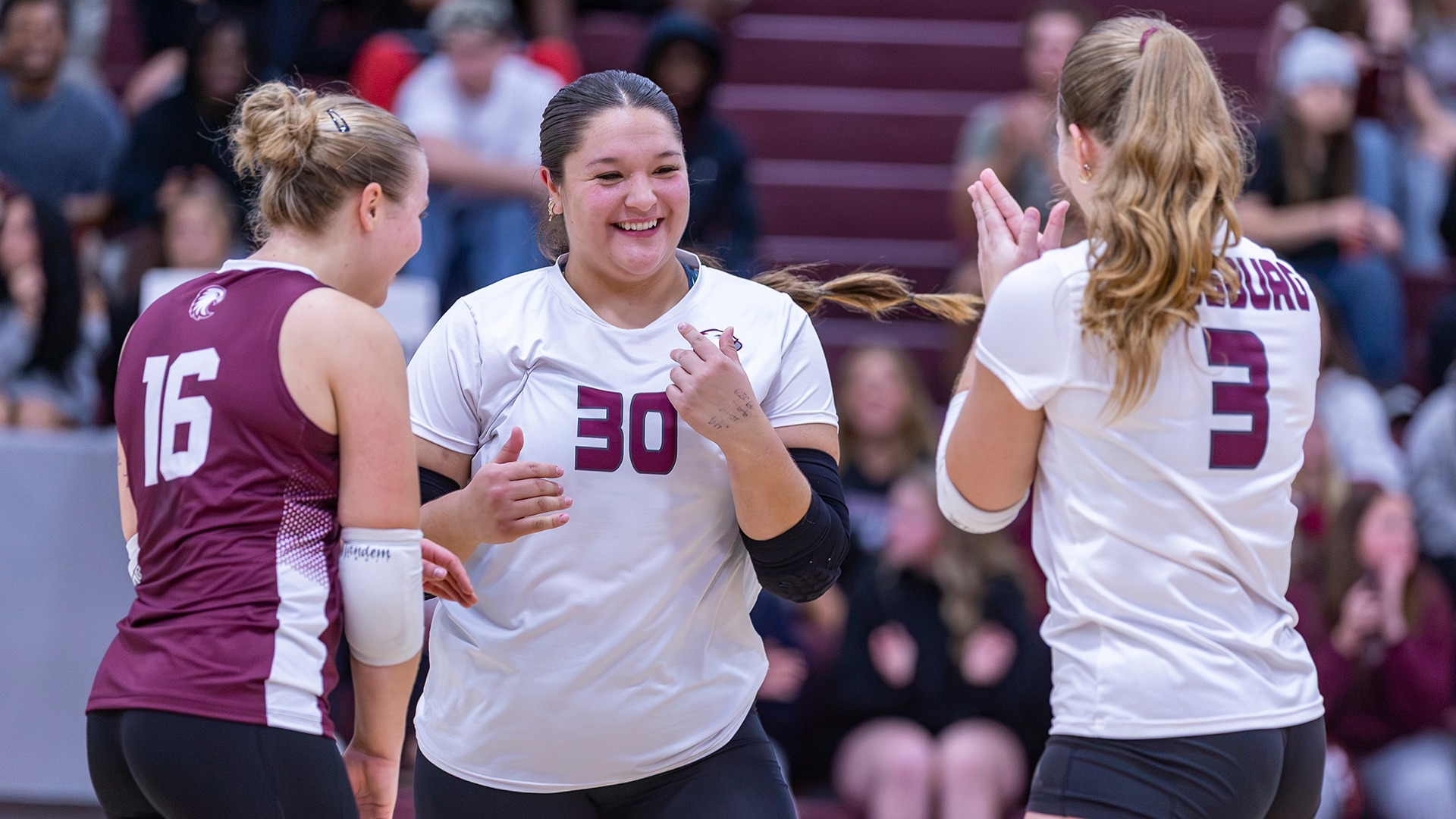 Lola Pilon, Maggie Lile and Ava Carlson celebrate a point during a 2026 Augsburg volleyball match.