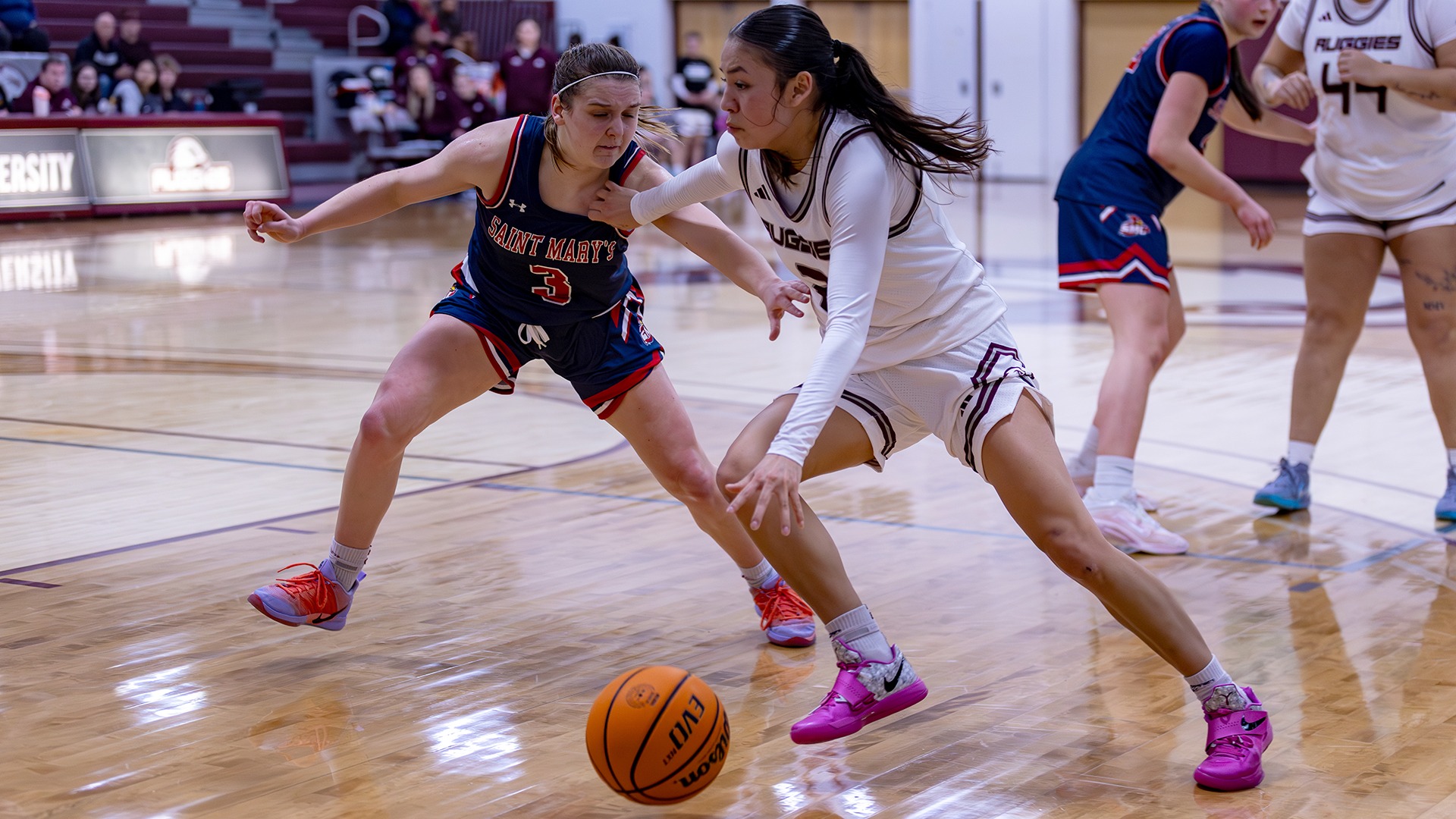 Wakinyela Bear drives against an opponent during a 2025-26 Augsburg women's basketball game.