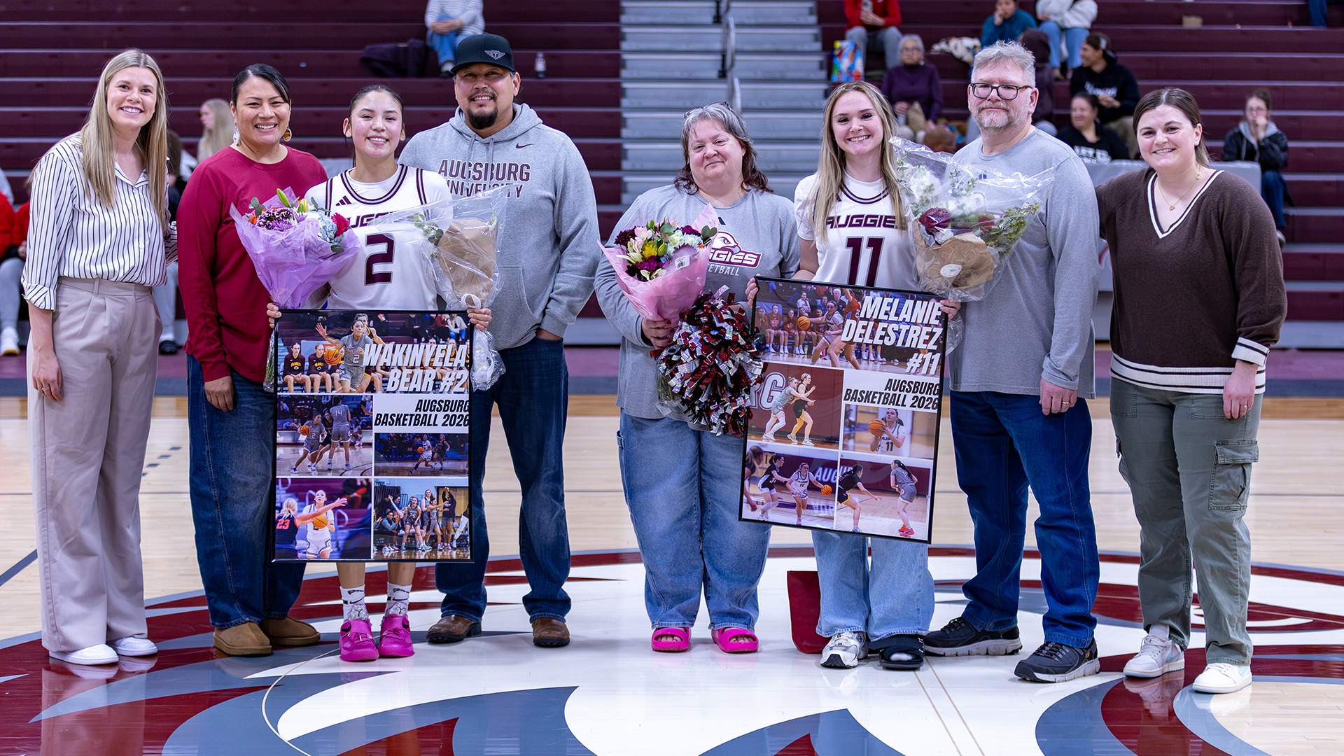 Augsburg women's basketball seniors Wakinyela Bear and Melanie Delestrez pose with their families and Augsburg coaches.