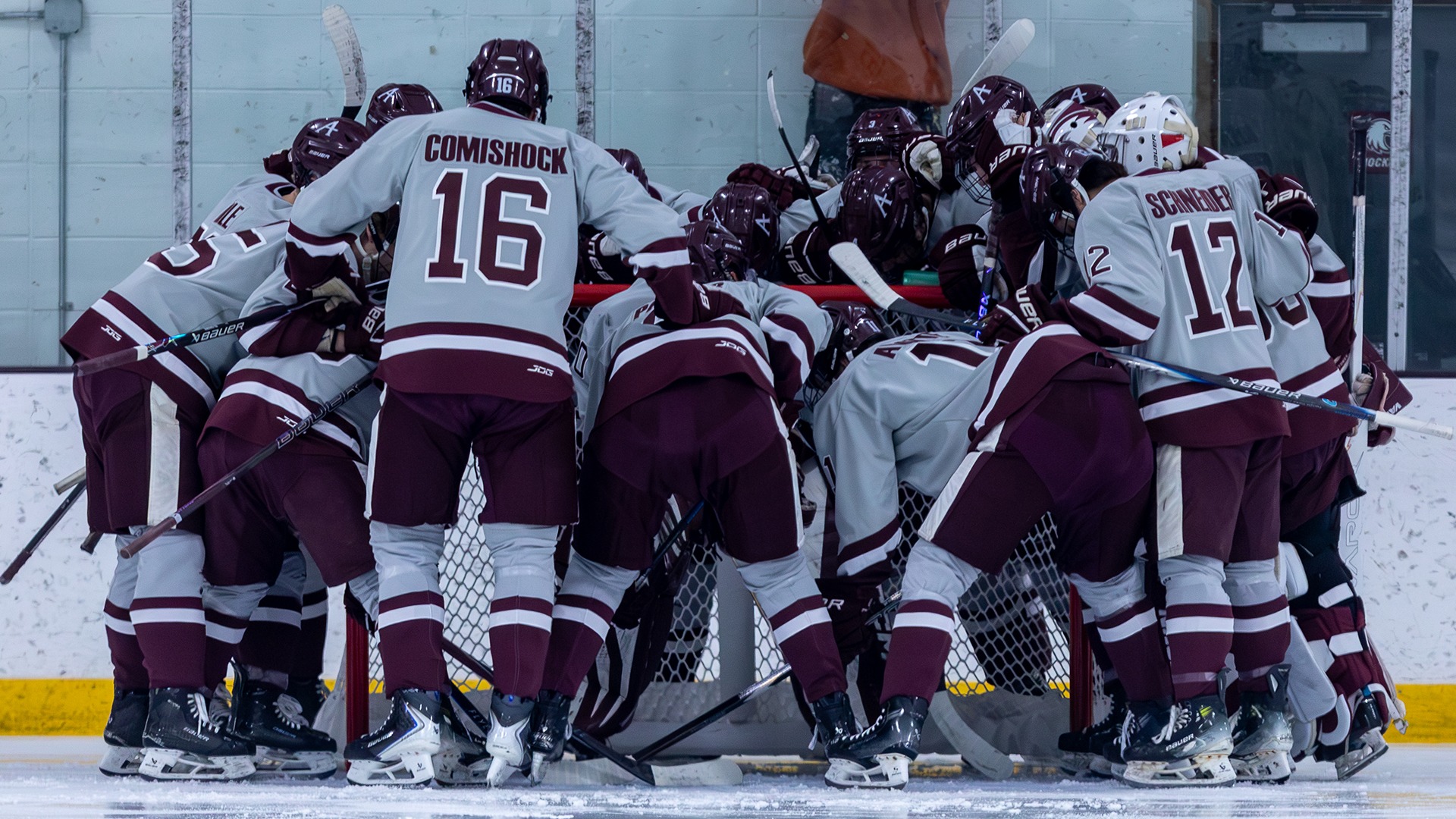Augsburg men's hockey team members gather in a huddle before a 2025-26 game.