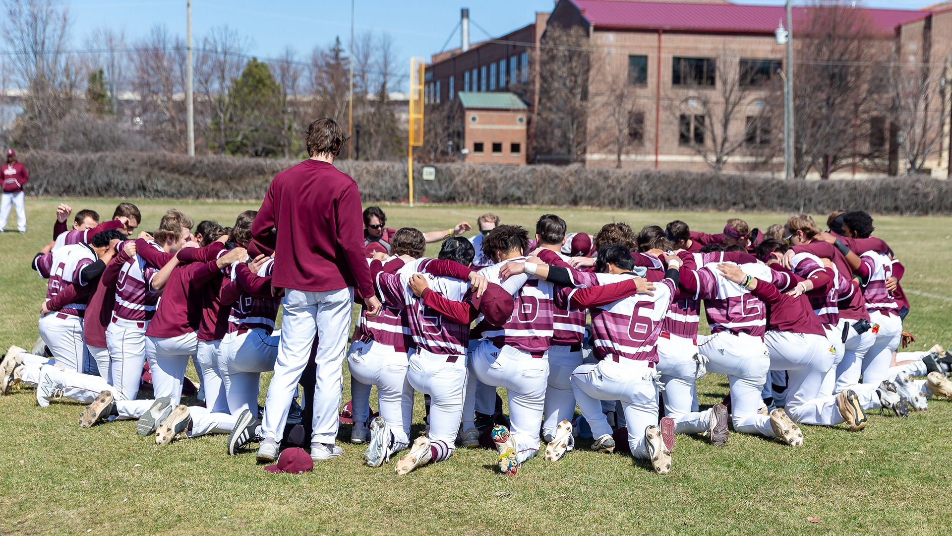 Augsburg baseball players gather in a huddle before a 2025 game.