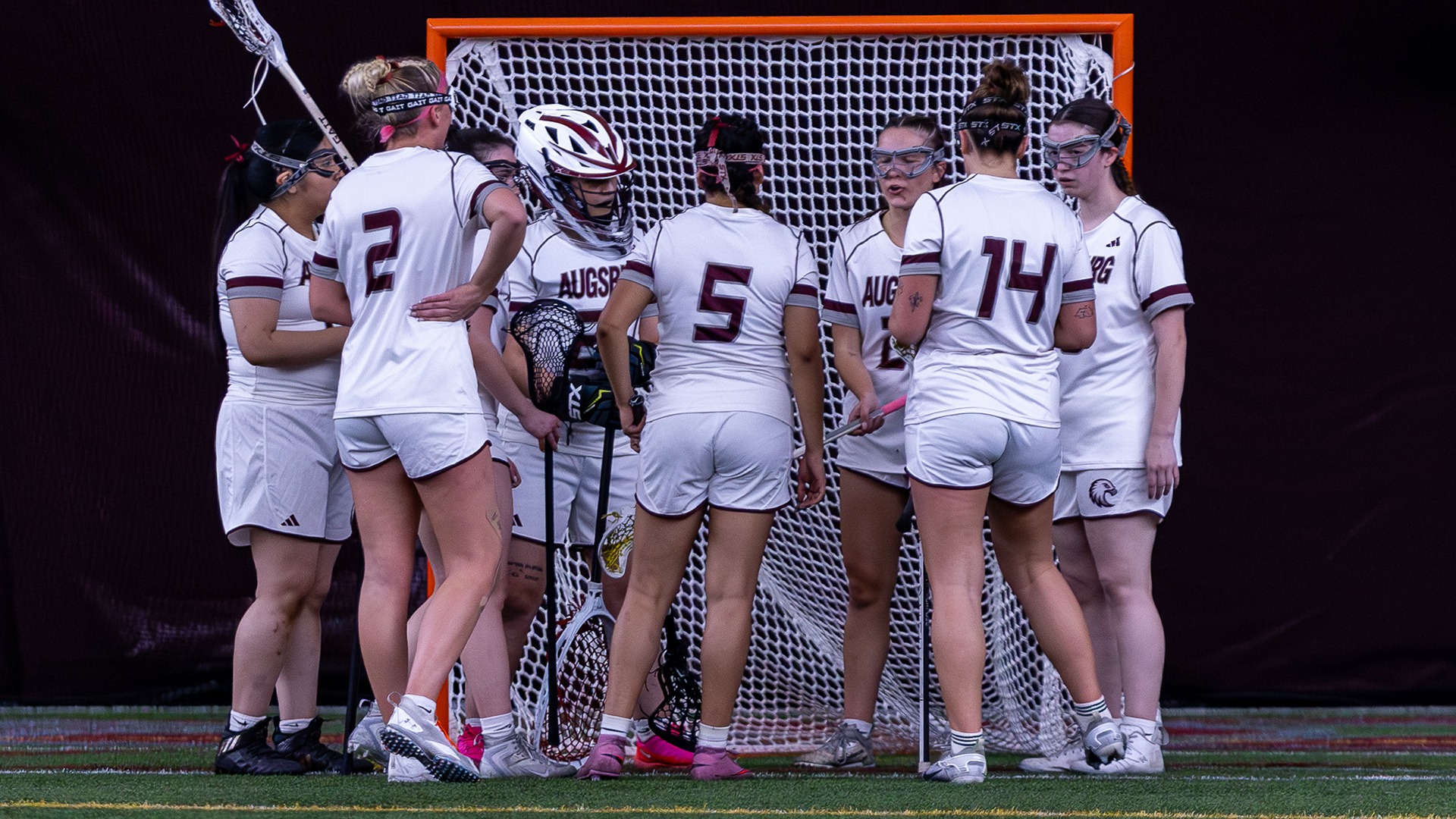 Augsburg women's lacrosse players gather in a huddle during a 2026 game.