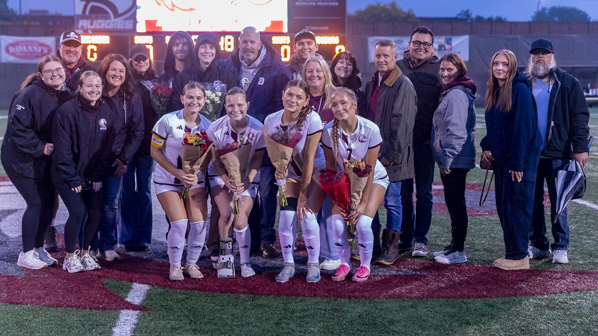 Augsburg's four women's soccer seniors pose with their families prior to a 2026 match.