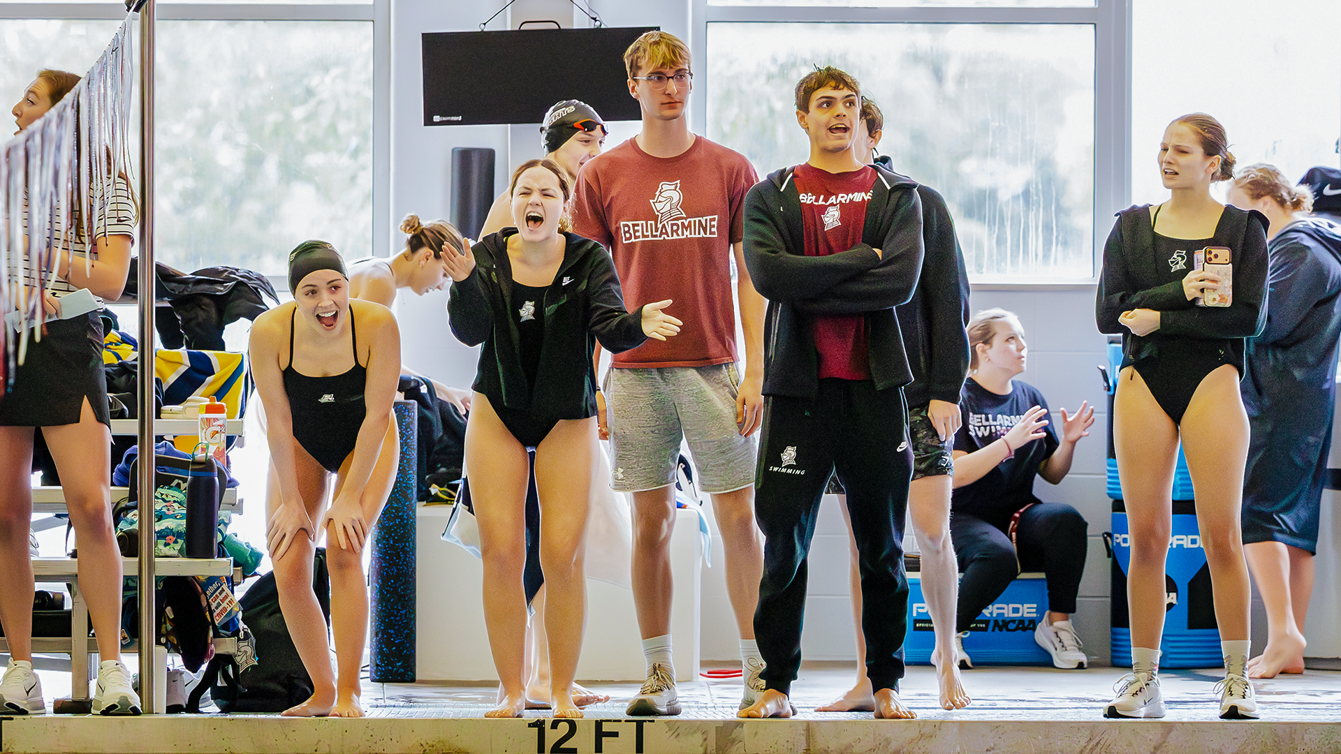Swimmers watch from the side of the pool