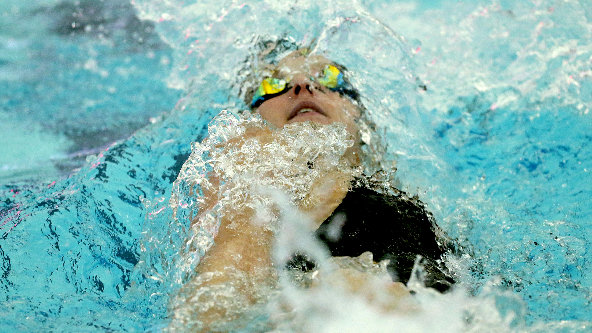 Female swimmer half submerged during the backstroke