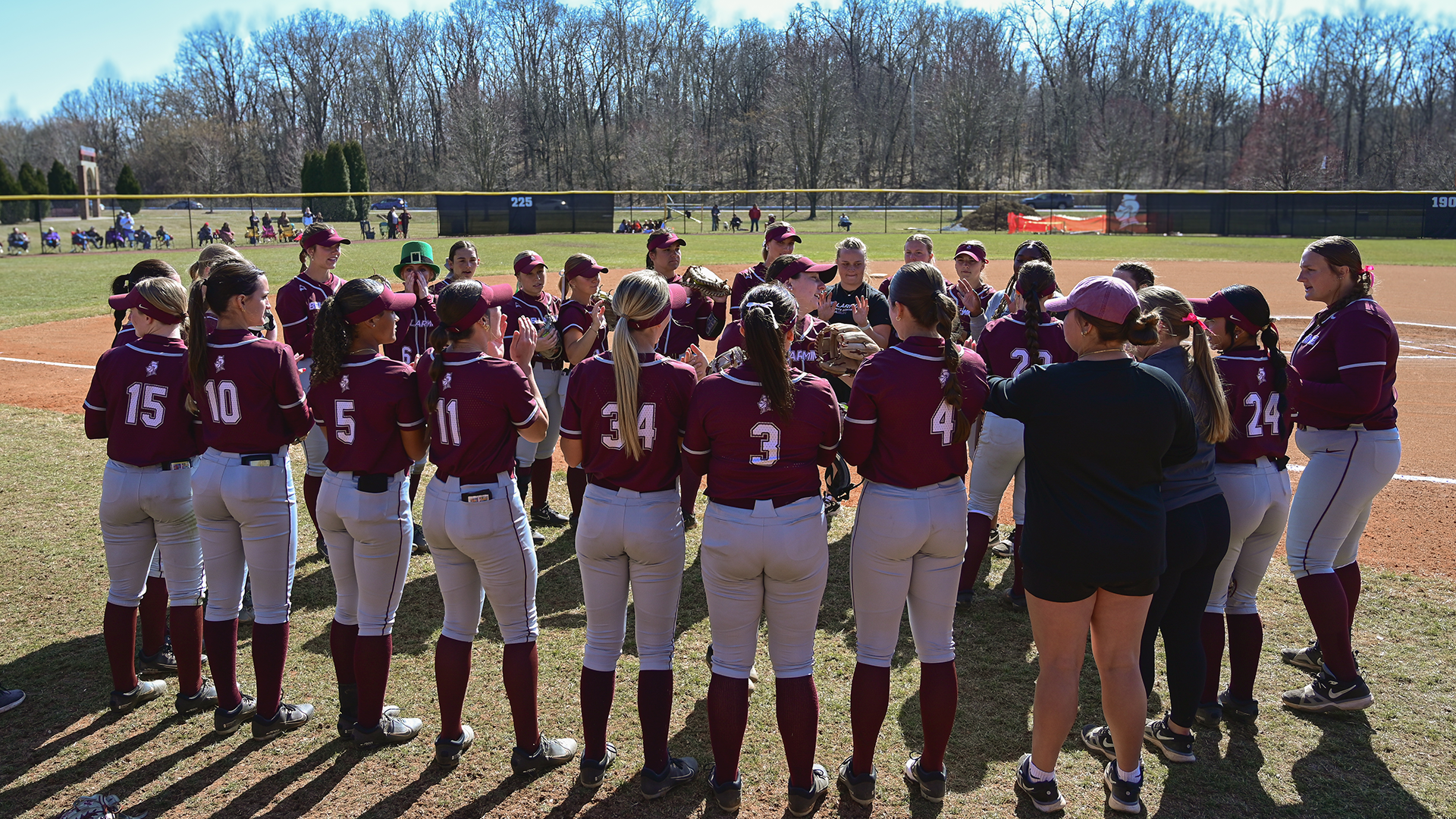 Softball team circles around the starters as lineups are announced before a game