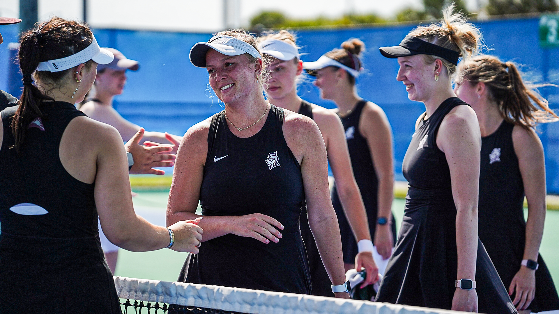 Women's tennis players smile and celebrate their win over Queens at the ASUN Championships