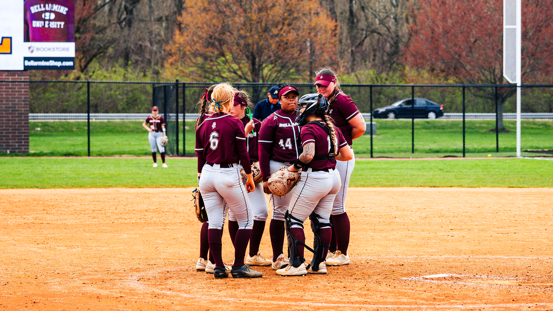 Softball players gather in the circle for a meeting during a game