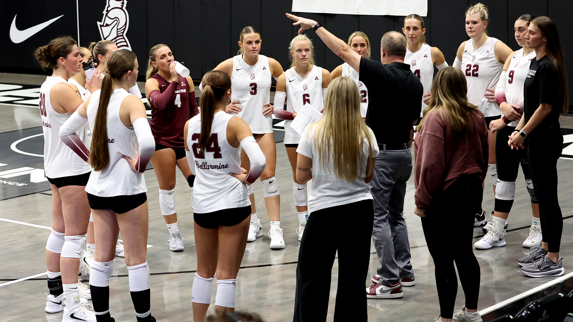 Volleyball team listening to head coach Rick Nold in a huddle