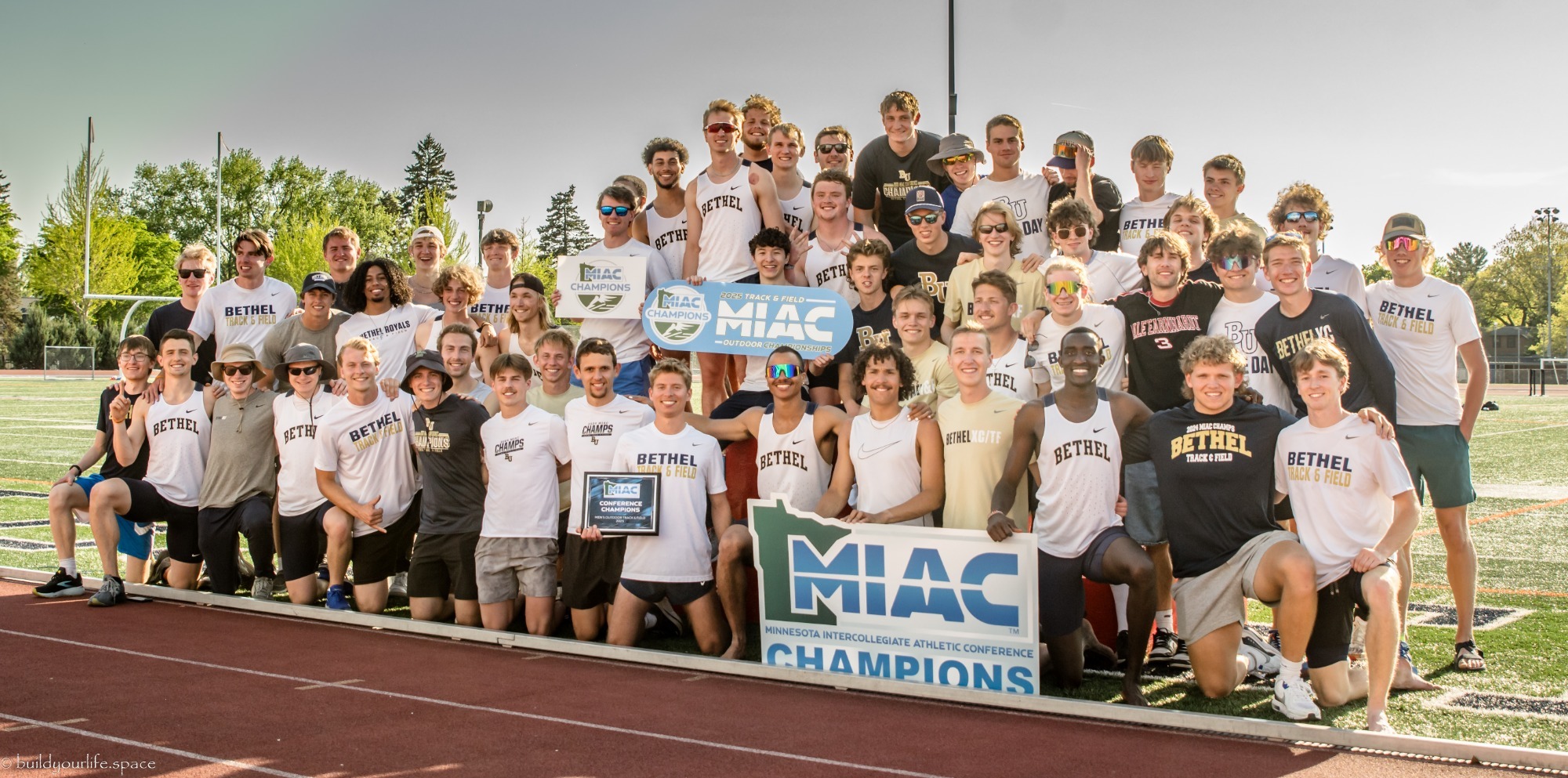 The men's track and field squad takes a picture with the MIAC Outdoor Track and Field trophy