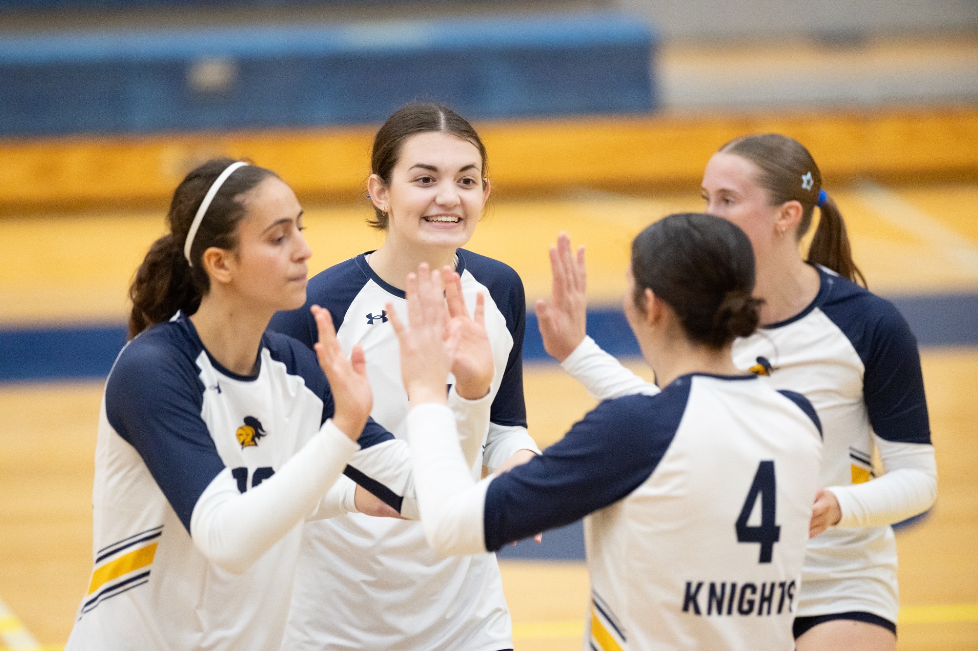 Sami Torresin, Jennifer Bricker, Rachel Bingham, and Megan Smith celebrate a point against St. Scholastica