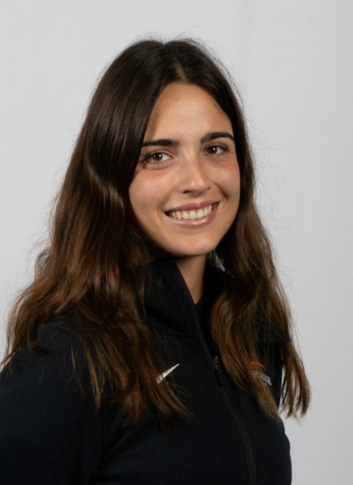 Julia Valls I Lope smiling for her women's tennis headshot, wearing a black warmup jacket. 