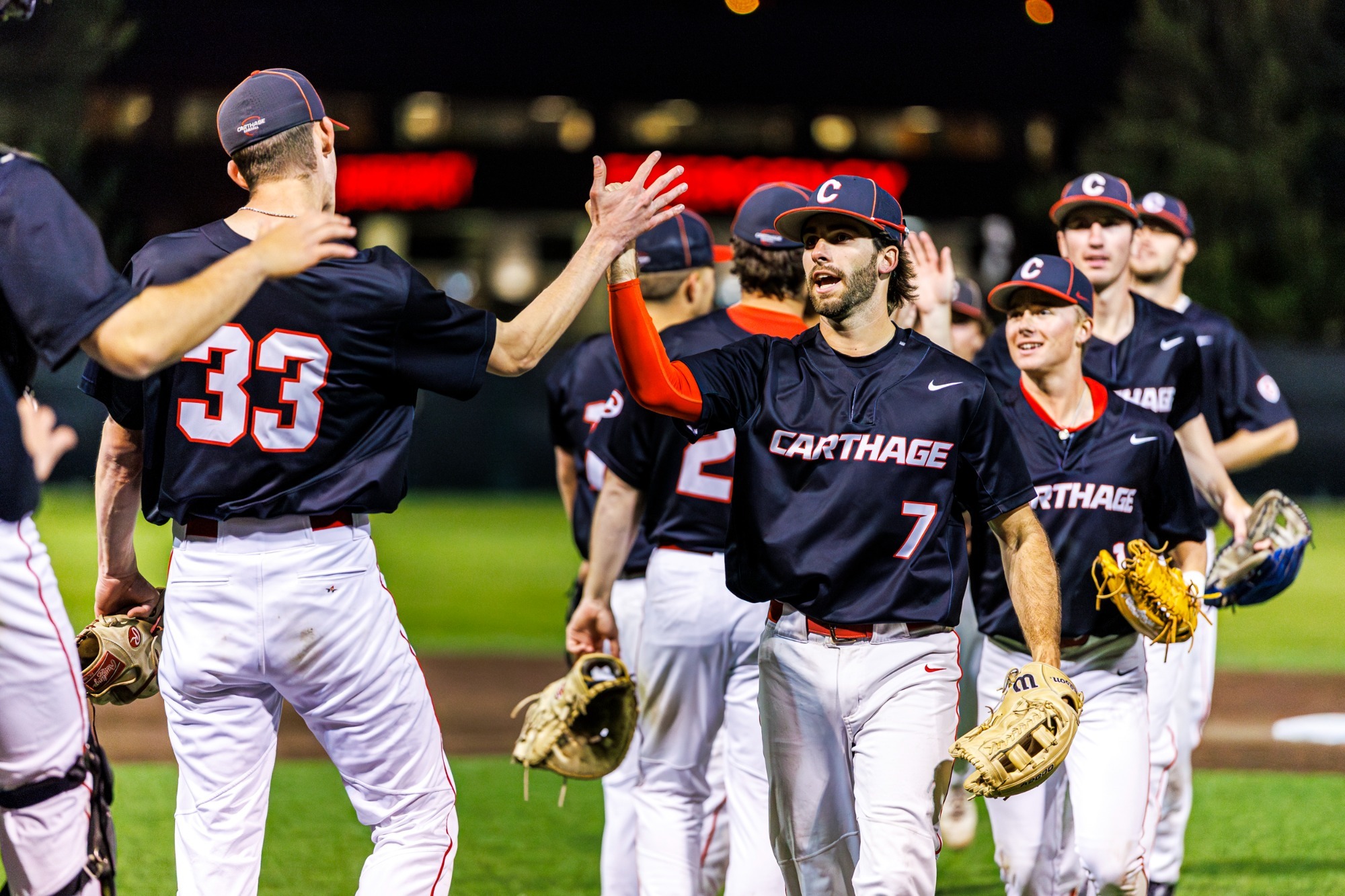 The baseball team high five after a win over Millikin