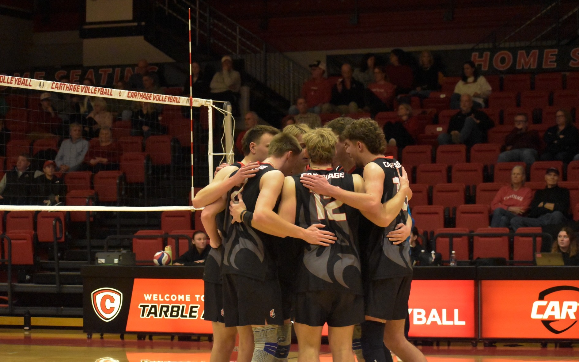 The men's volleyball players gather after a point