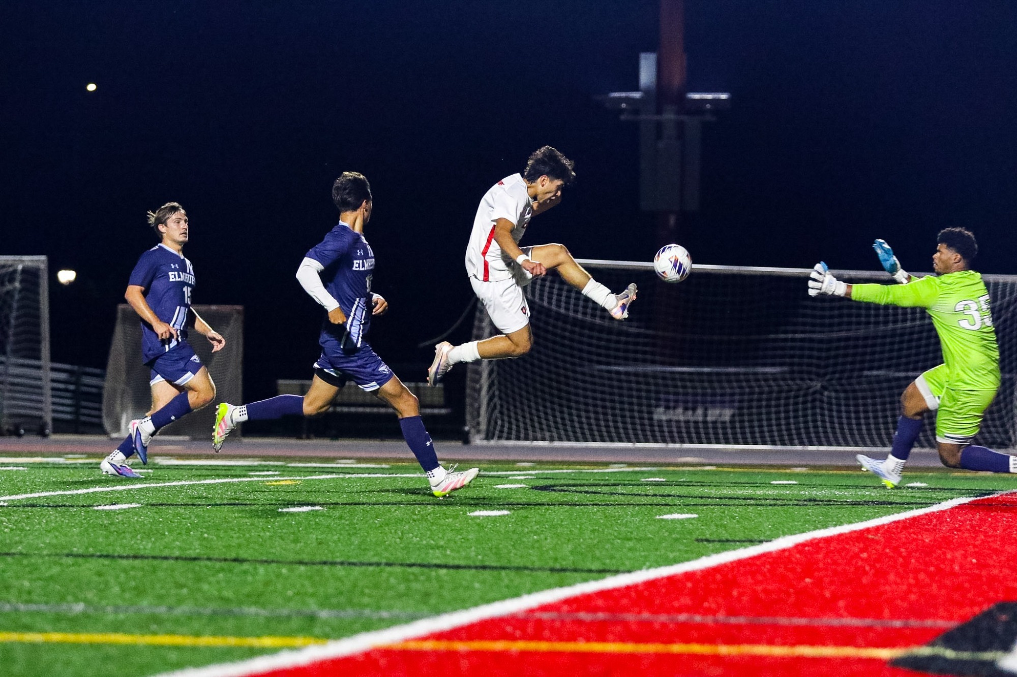 Carthage men's soccer forward tries to sneak a ball past the keeper with a high kick. 