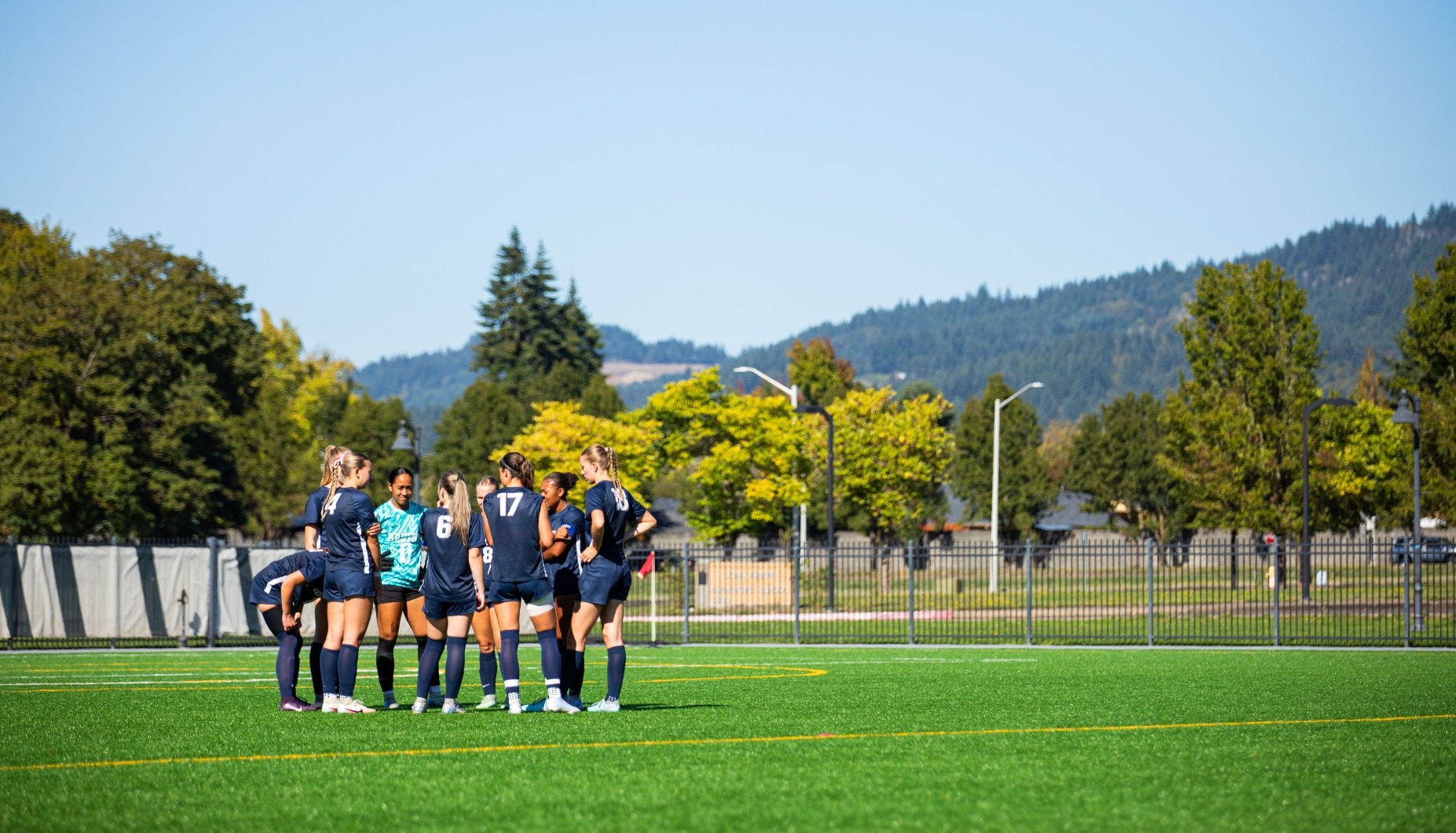 Women's soccer team huddled together before a game in the sun on the field