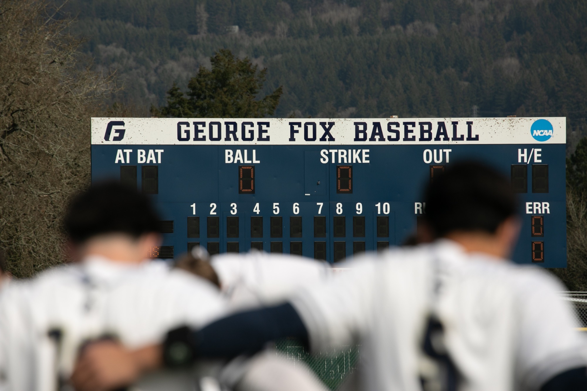 Baseball players stand in front of the scoreboard