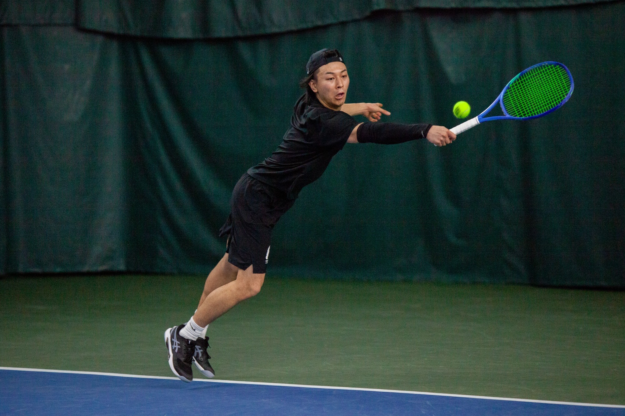 Keita Shoji reaching to return tennis ball with backhand