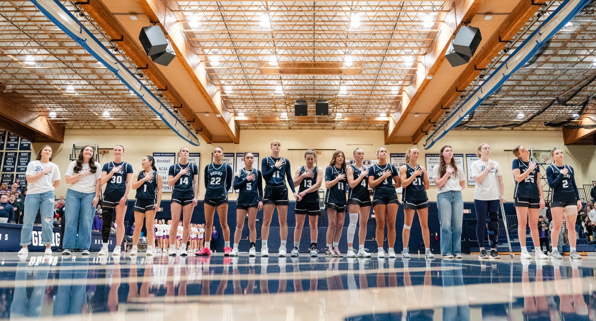 Women's basketball team putting hands on hearts during national anthem