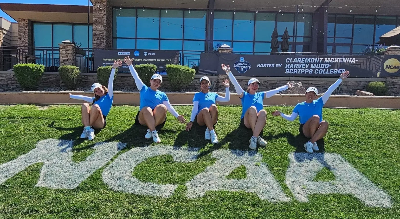 Women's Golf team stands in front of NCAA painted on grass