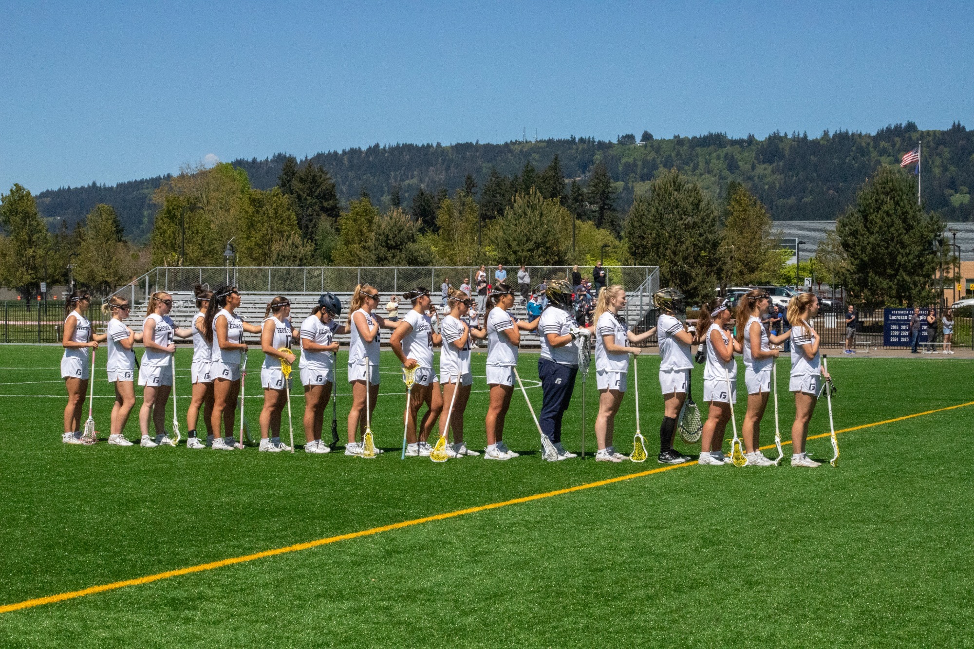Lacrosse team standing facing flag during anthem