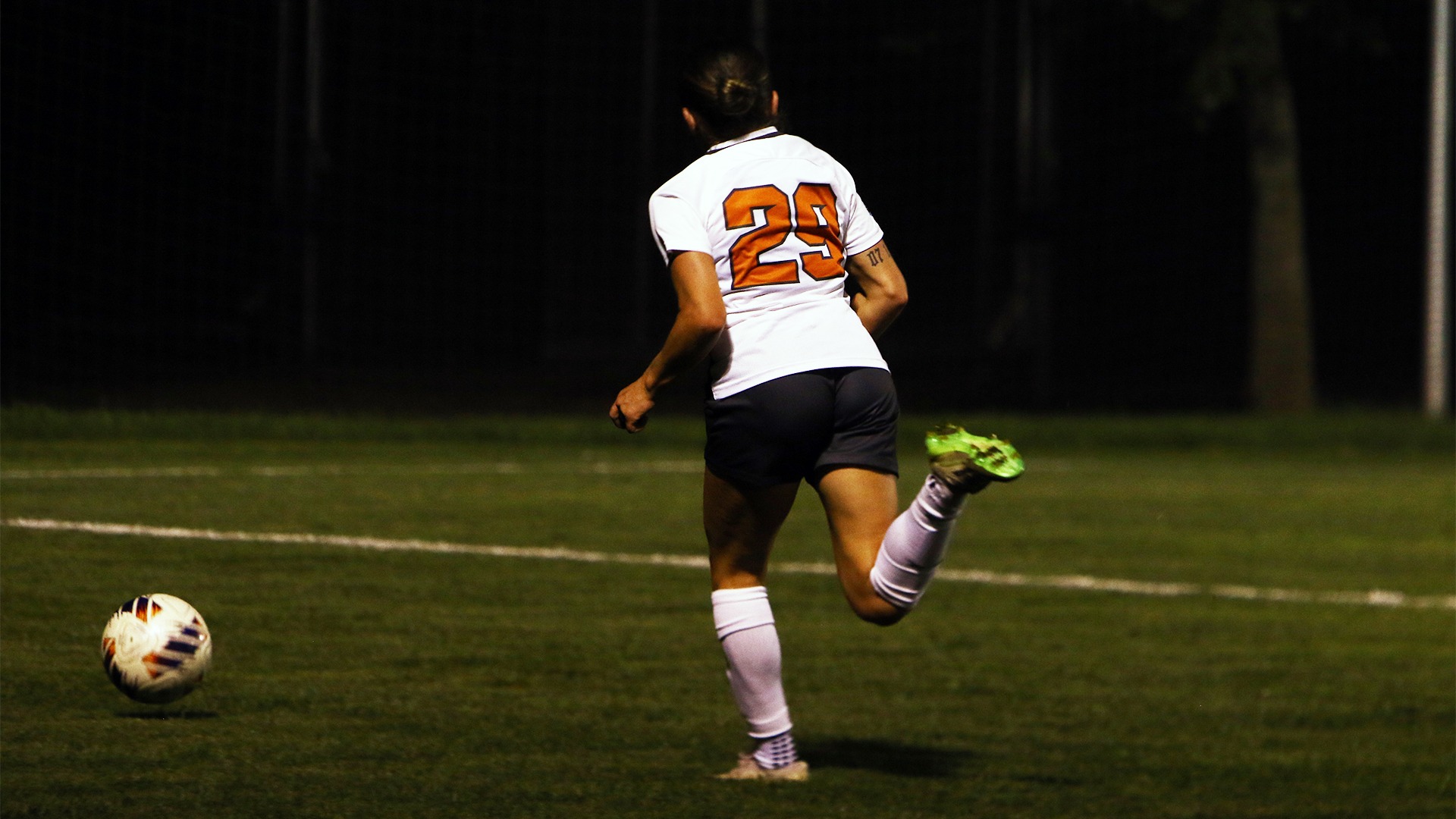 Angie Russo in white jersey dribbling ball