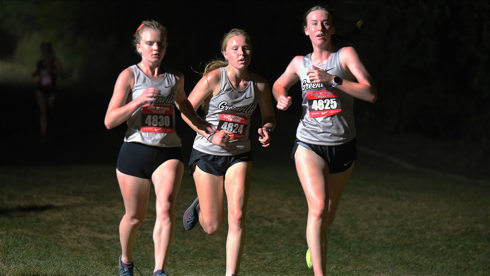 Three Greenville Women's Cross Country runners running in pack in grey jerseys 