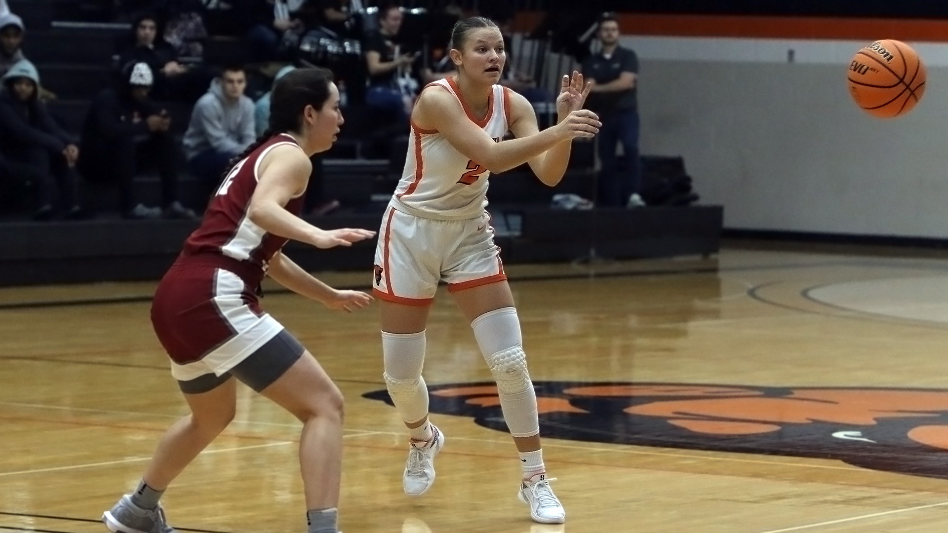 Cortney Brummer in white jersey passing basketball to left 