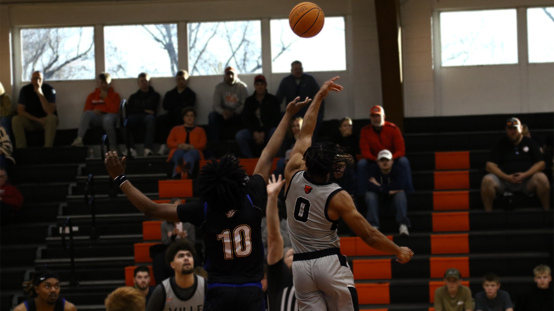 Tim Lofton in grey jersey jumping for tip off against spalding player wearing black