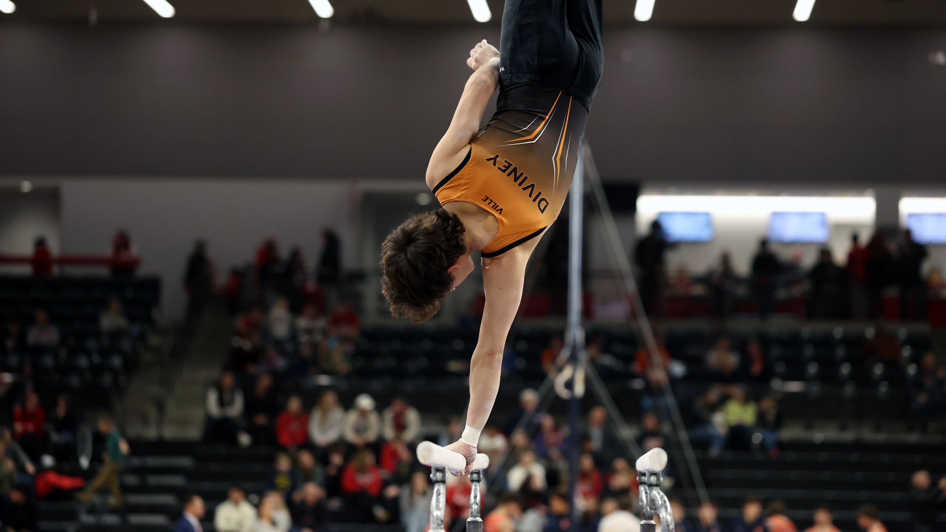 Diviney upside down using one hand on parallel bars