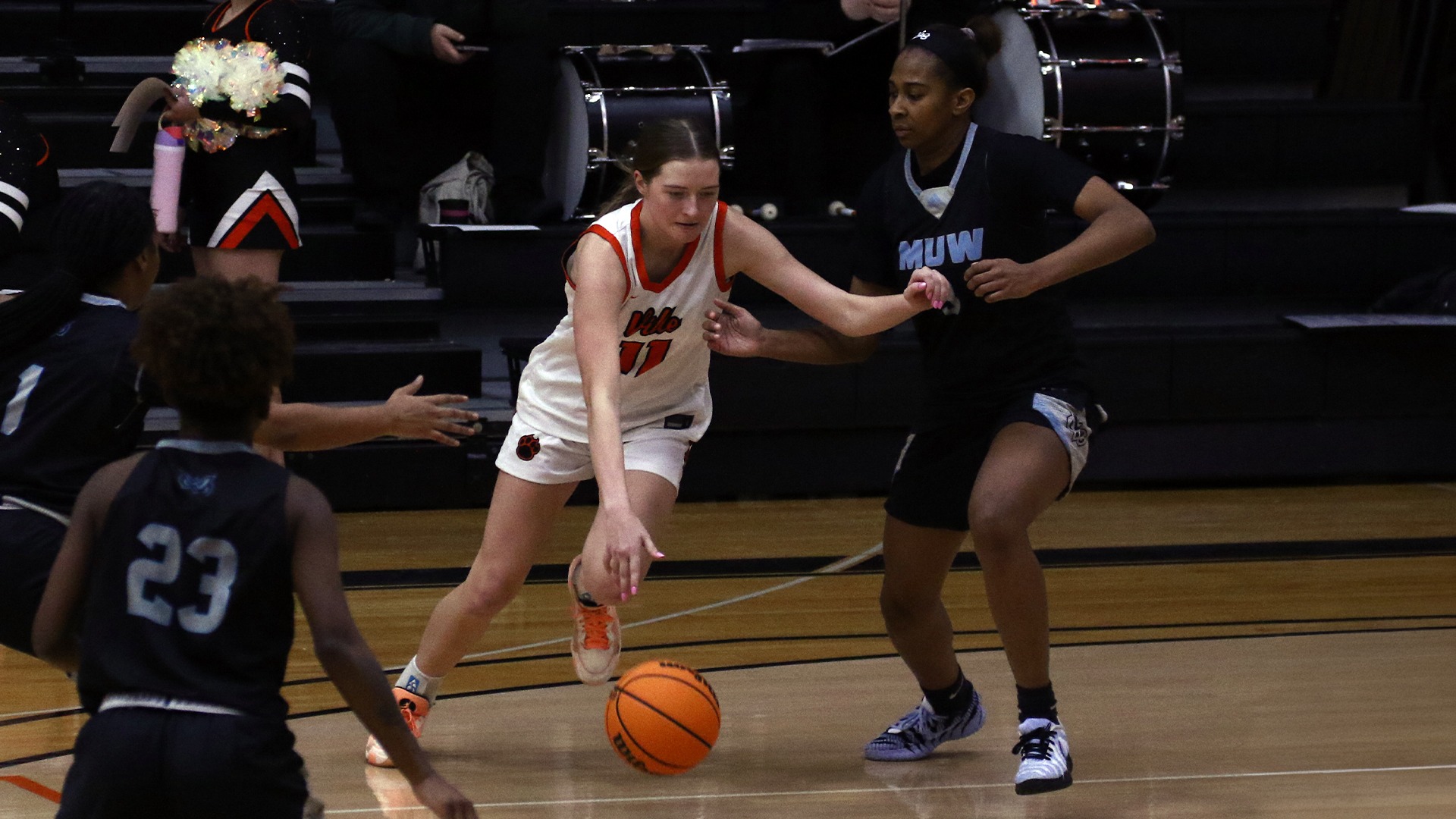 Addie Goheen in white jersey dribbling ball around MUW player
