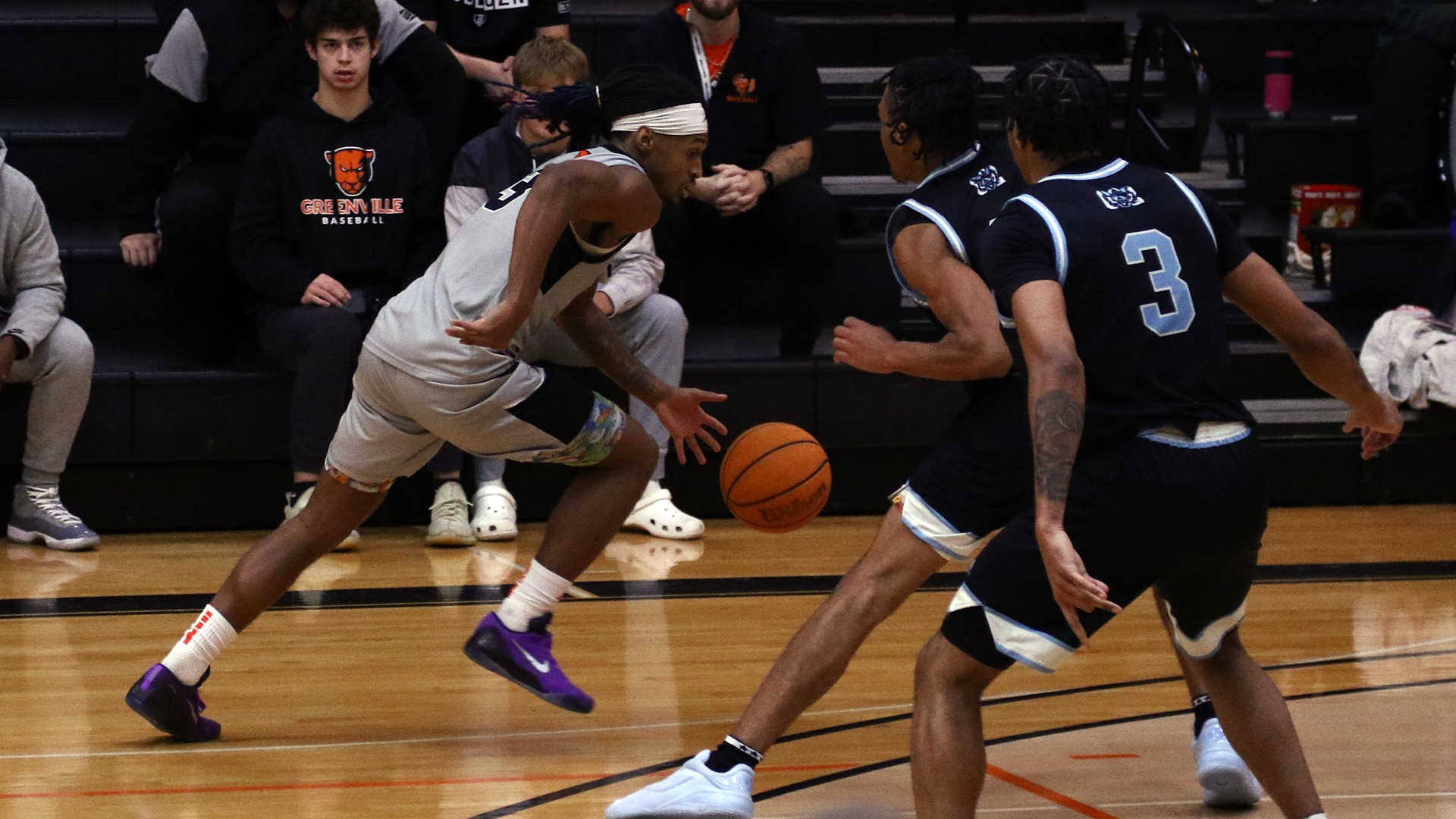 Elliott Mobley in grey jersey dribbling ball around MUW player