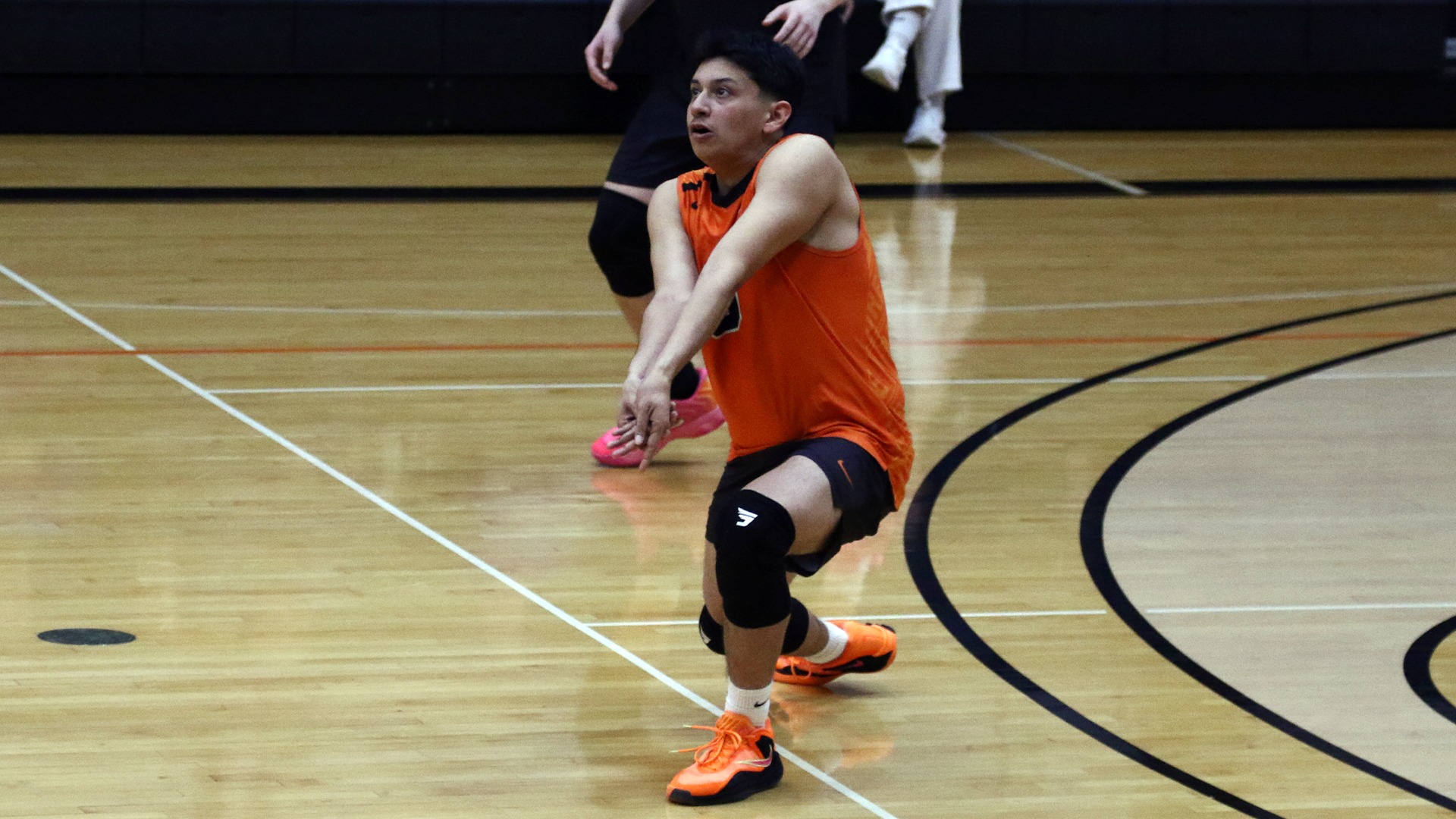 Jay Ramirez in orange jersey, black shorts in passing position awaiting ball