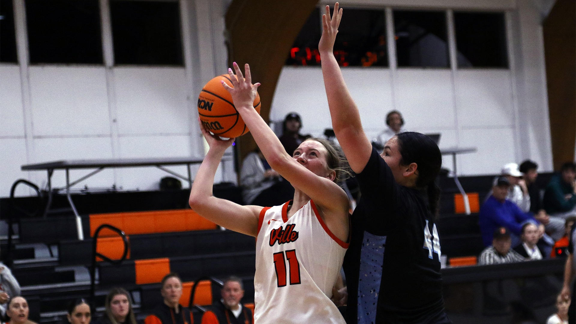 Addie Goheen in white jersey going for a layup against Westmin player in black