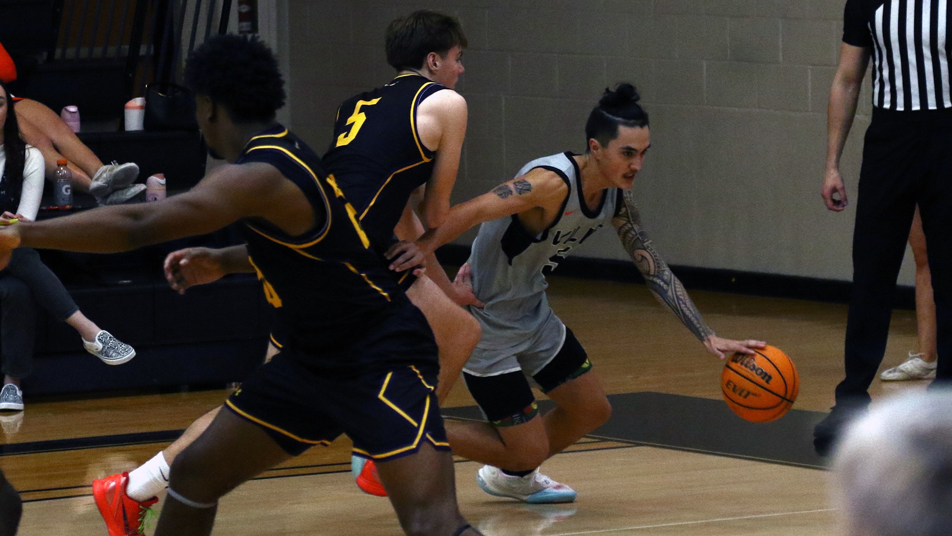 Brandon Tully in grey jersey dribbling ball around opposing player in black
