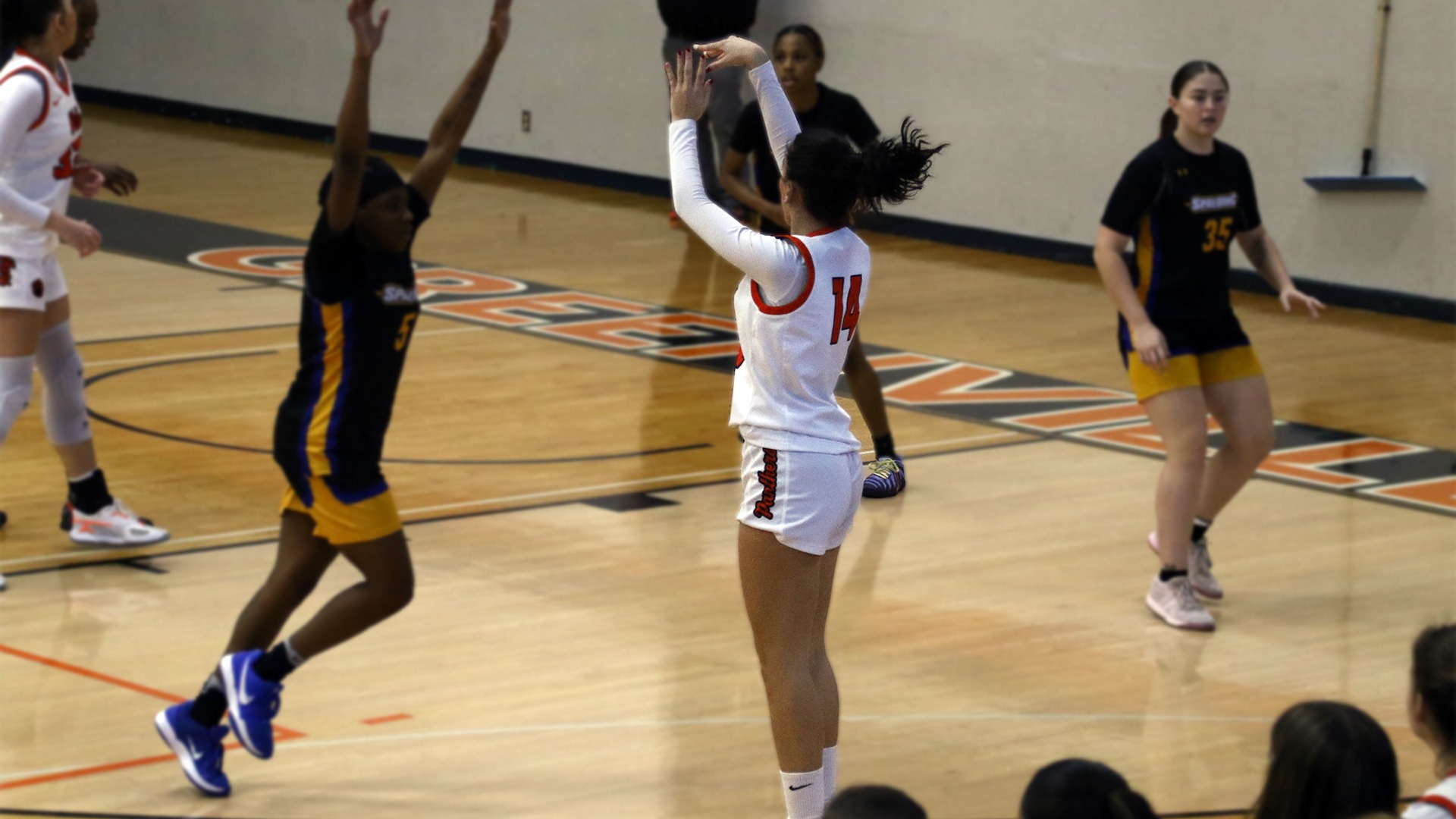 Lucia Caballero in white jersey shooting a three