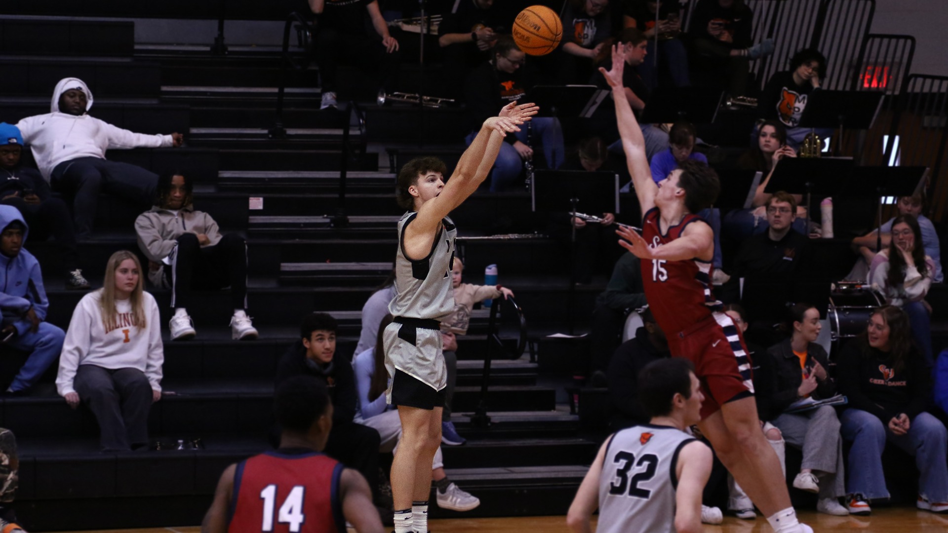 Caleb Johnson in grey jersey shooting three over Lyon player in red