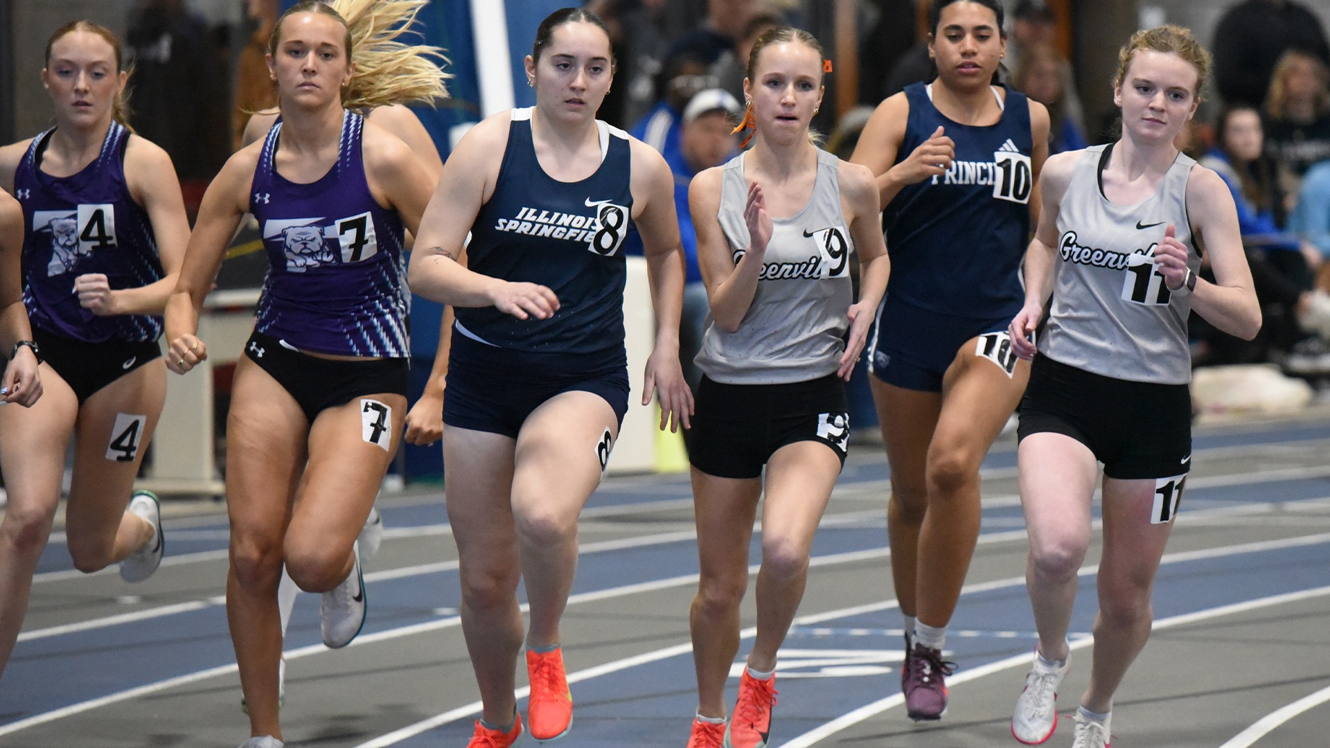 Norah Atkins in grey uniform running against other competitors indoors