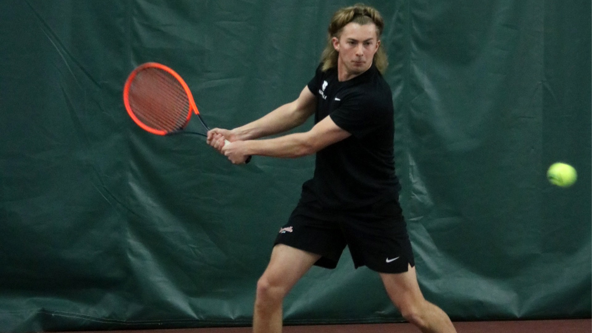 Colton Hulme in all black with orange racquet hitting a forehand
