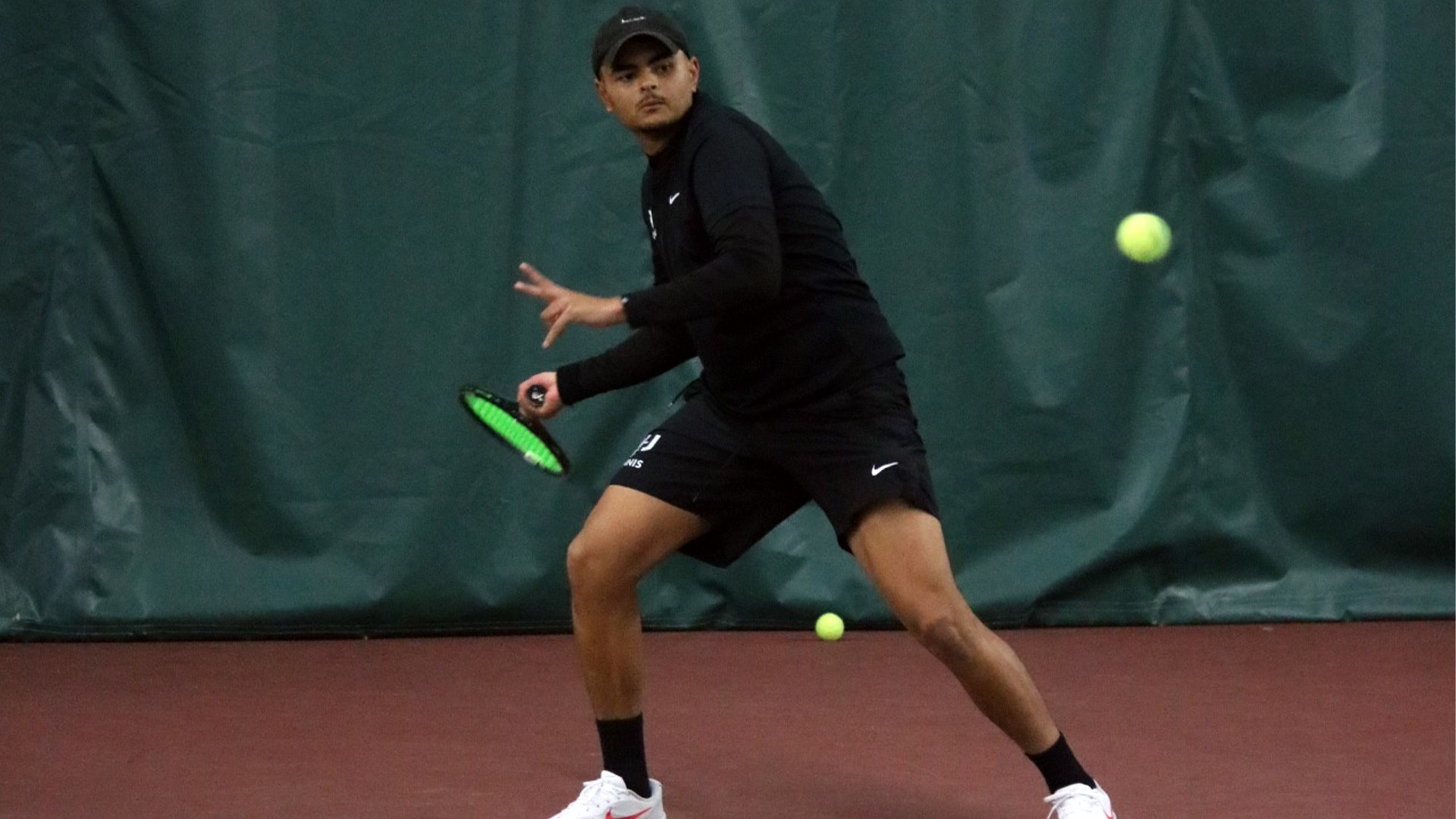 Panther men's tennis player in all black hitting forehand