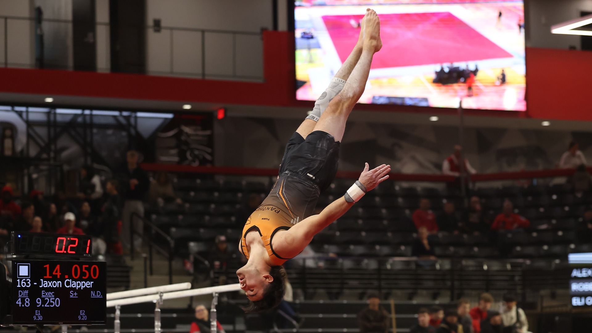panther gymnast in orange uniform upside down in air