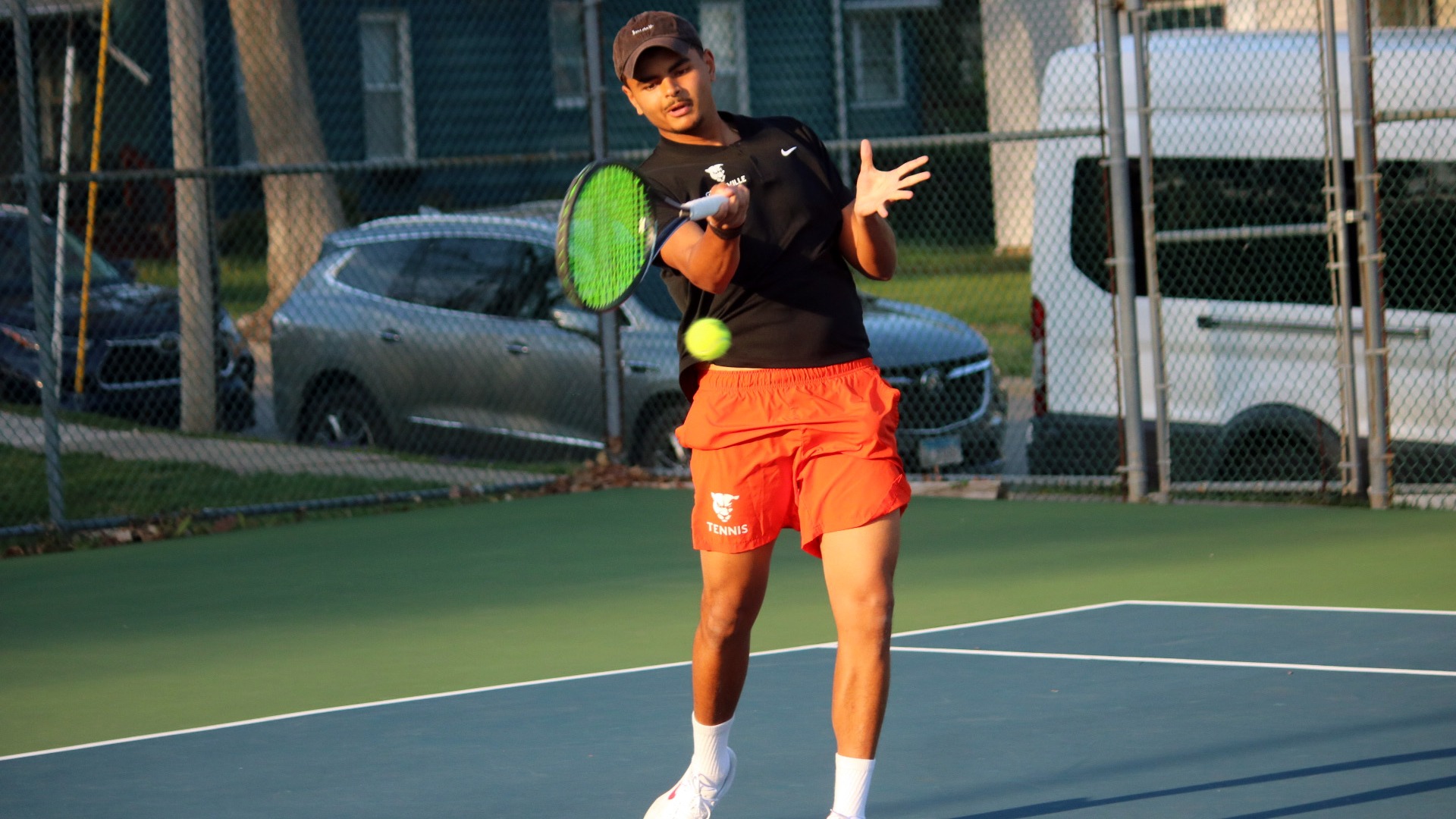 MTEN player in black shirt, orange shorts hitting forehand