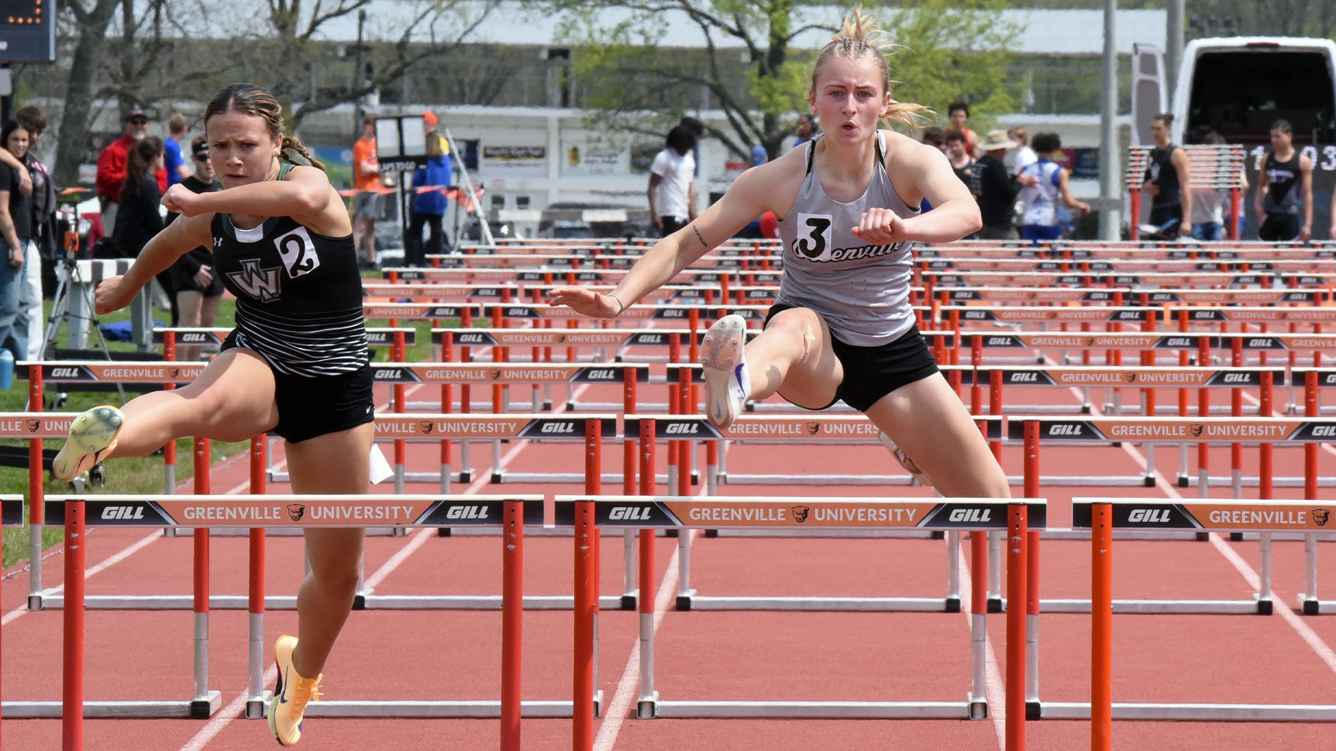 Madison Kacevicius hurdling in grey uniform